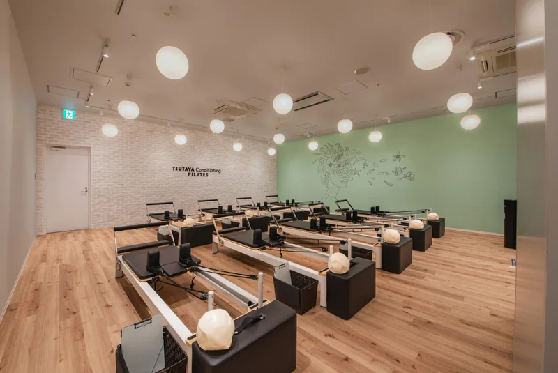 TSUTAYA Conditioning PILATES 新静岡セノバ店の内観。緑の壁と複数のリフォーマー
